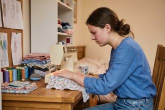 Jeune femme travaillant à une machine à coudre dans une chambre chaleureuse